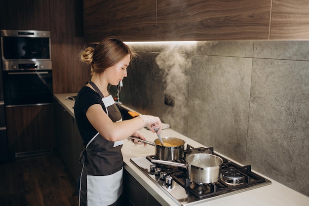 Mooie jonge huisvrouw kookt in de buurt van het bord met snoep in een moderne keuken