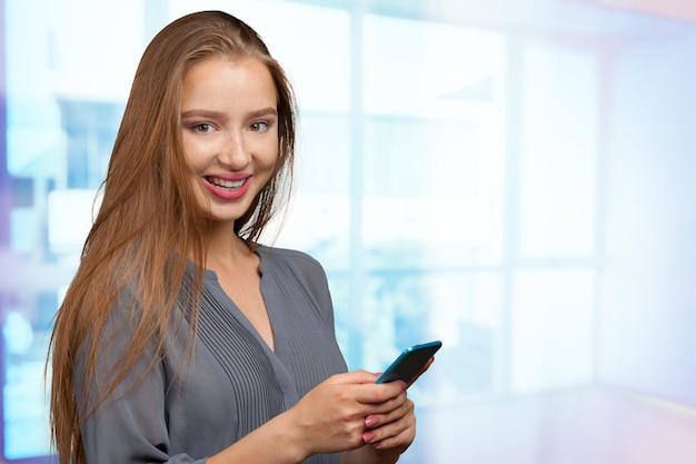 Mooie jonge Kaukasische bedrijfsvrouw met slimme telefoon