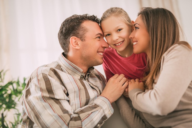 Mooie jonge lachende familie ontspannen op de bank in de woonkamer.