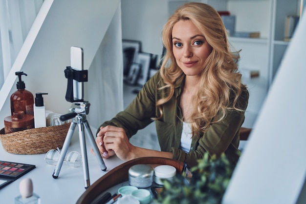 Mooie jonge lachende vrouw vloggen over schoonheidsproducten en kijken naar de camera