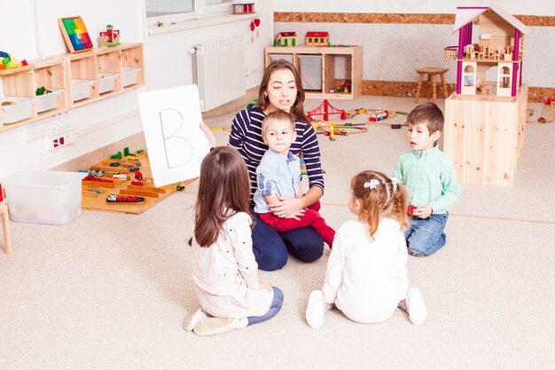 Mooie jonge leraar met brief kleuters, kinderen zitten in een cirkel