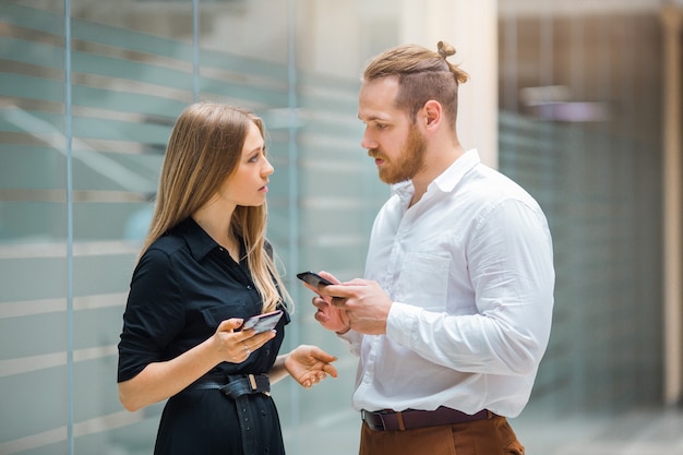 mooie jonge man en vrouw met telefoons in hun handen