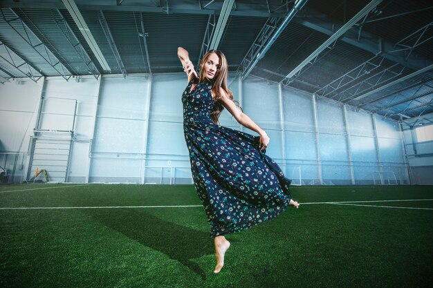 Mooie jonge mannequin in een jurk in een groot sportstadion poseren