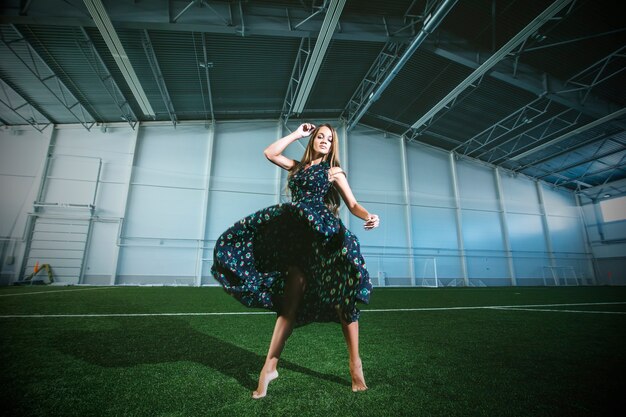 Mooie jonge mannequin in een jurk in een groot sportstadion poseren