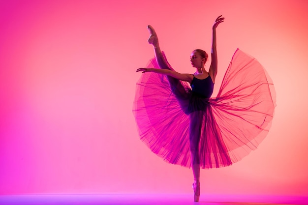 Mooie jonge meisjesballerina in pointe-schoenen en een zwempaksilhouet op een heldere rode achtergrond.