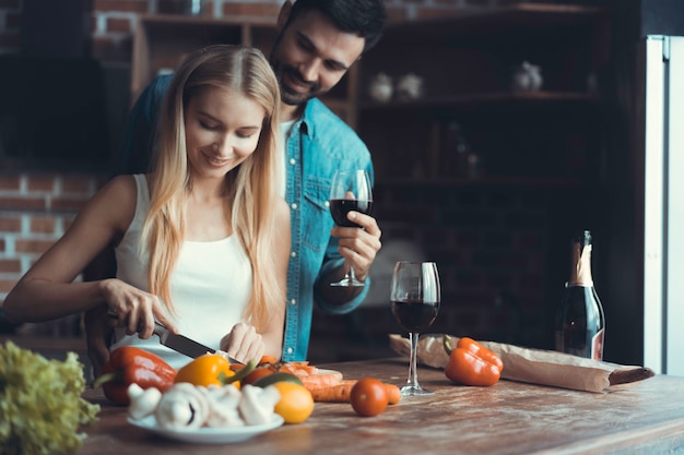 Mooie jonge mensen praten en glimlachen tijdens het koken van gezond voedsel in de keuken thuis