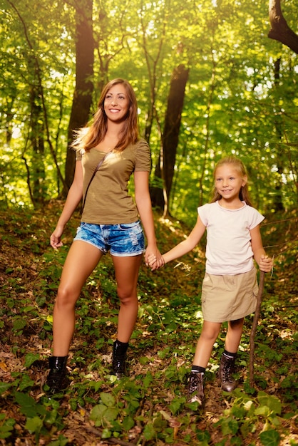 Mooie jonge moeder en haar dochter wandelen door het bos.