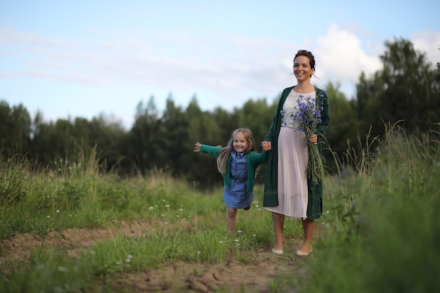 Mooie jonge moeder met dochter die op een landelijke weg loopt