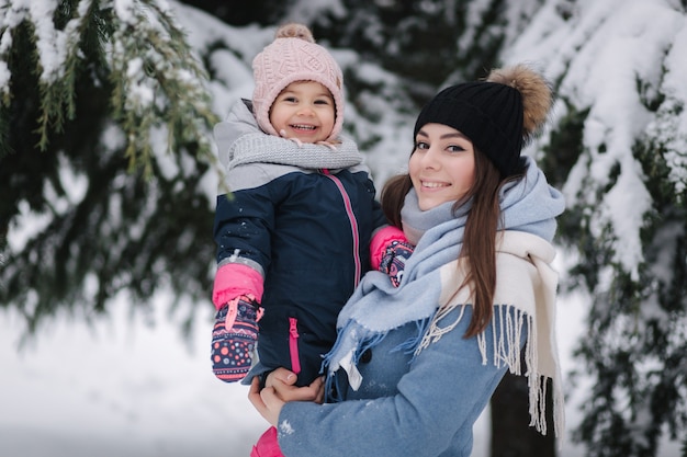 Mooie jonge moeder met haar schattige dochter in winter park