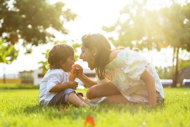 Mooie jonge moeder met haar zoon die yoghurt in het park eet.