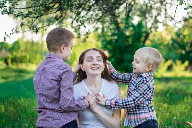 Mooie jonge moeder met twee zonen kinderen knuffelen moeder gelukkige jeugd en moederschap