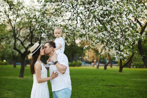 Mooie jonge ouders en hun schattige zoontje vermaken zich in het groene park