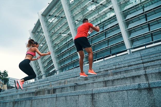 Mooie jonge paar in sportkleding springen en joggen tijdens het sporten op de trappen buiten