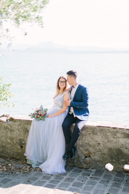 Mooie jonge paar omarmen en wandelen in de tuin van het Scaliger-kasteel op de achtergrond van het Gardameer. Sirmione, Italië