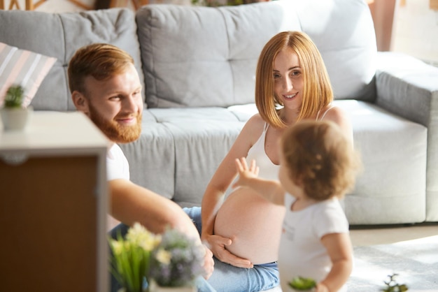 Mooie jonge paar ouders tijd doorbrengen met dochtertje thuis Vrouw verwacht baby Concept van zwangerschap familie liefdesrelatie ouderschap en kindertijd