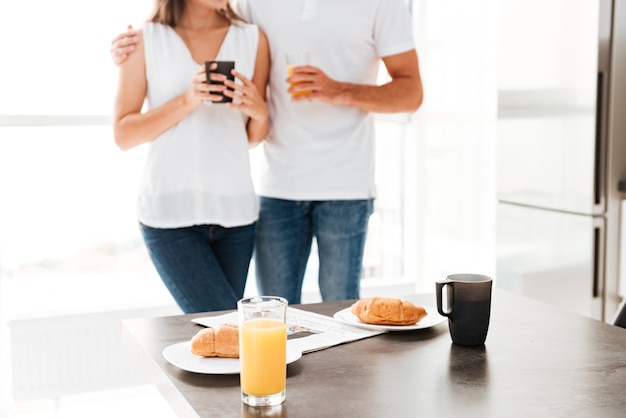 Mooie jonge paar staande voor de tafel met ontbijt op de keuken