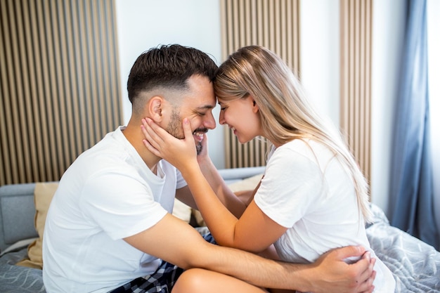 Mooie jonge paar thuis Knuffelen, zoenen en genieten van tijd samen doorbrengen Gepassioneerd mooi paar in slaapkamer genieten van voorspel