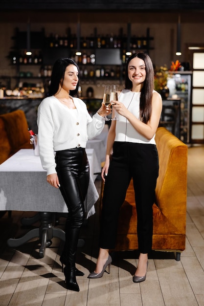 Mooie jonge paar vrouwen met glazen champagne vieren feest in luxe restaurant