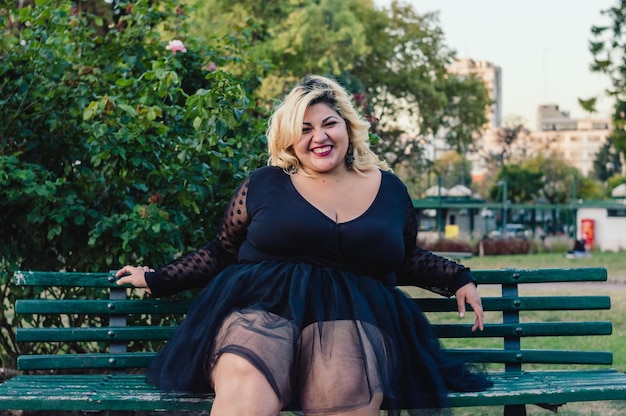 Mooie jonge plus size vrouw zit blij naar de camera te kijken en te lachen