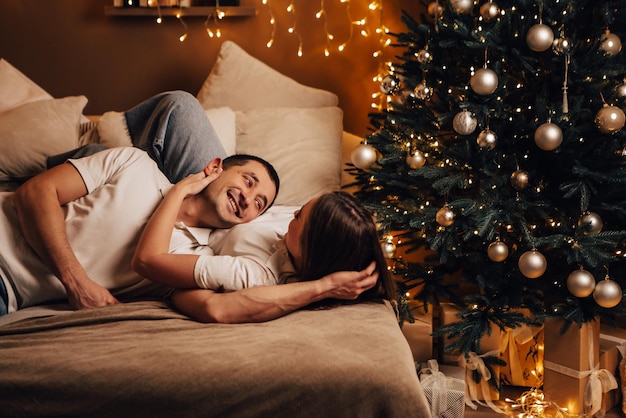 Mooie jonge romantische paar liggend op bed slingers zoenen knuffelen thuis gezellige interieur sfeer