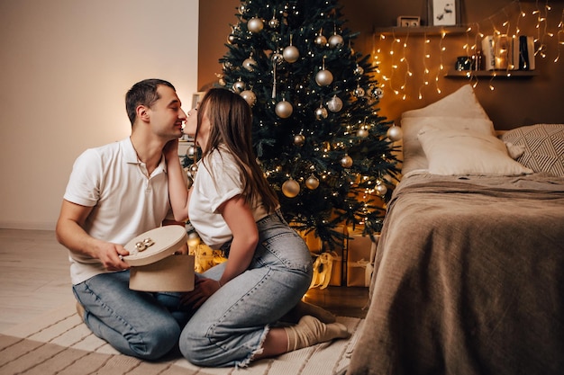 Mooie jonge romantische paar zitten open geschenken presenteert slingers thuis gezellige interieur sfeer