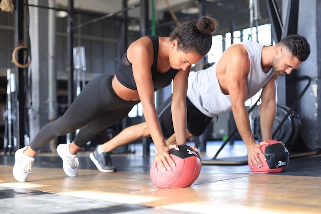 Mooie jonge sport paar werkt met medicijnbal in de sportschool.