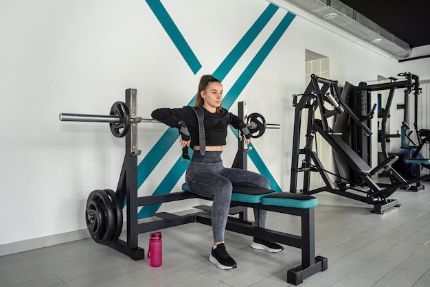 Mooie jonge sportvrouw traint met een kabel-crossover-trainer in een fitnesszaal