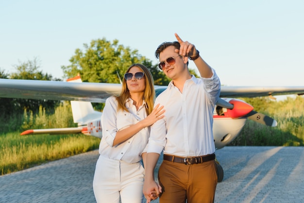Mooie jonge stijlvolle paar in officiële kleren permanent in privé vliegtuig
