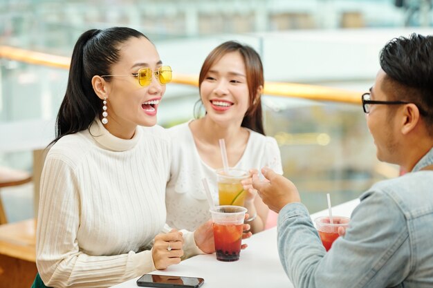 Mooie jonge vietnamese vrouw ijsthee drinken en praten met vriend tijdens vergadering