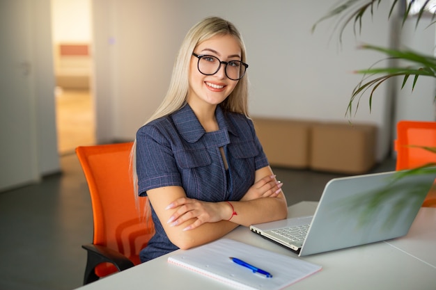 mooie jonge vrouw aan de tafel met laptop op kantoor