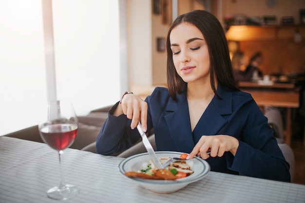 Mooie jonge vrouw aan tafel zitten en salade eten