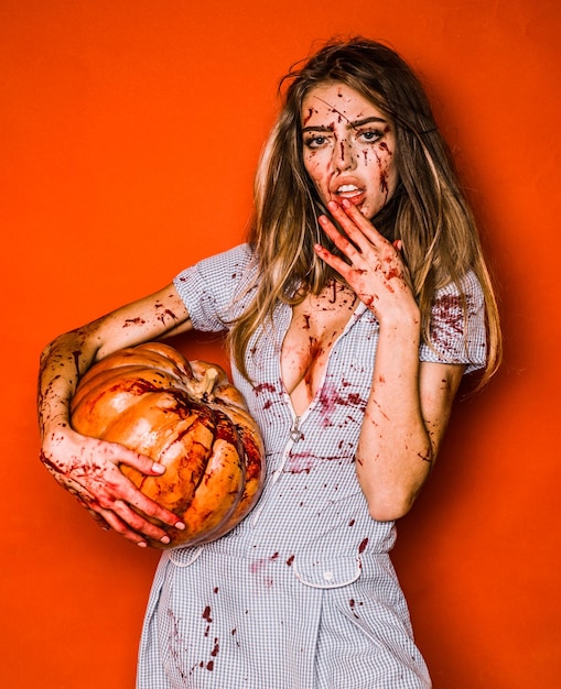 Mooie jonge vrouw als sexy vampier halloween-concept eng bloedig zombiemeisje met pompoen woman