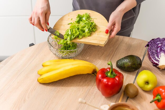 Mooie jonge vrouw bereidt groentesalade in de keuken. Thuis Koken.