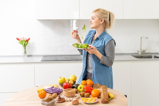 Mooie jonge vrouw bereidt groentesalade in de keuken. Thuis Koken.