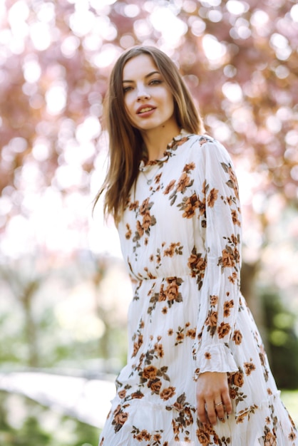 Mooie jonge vrouw bij een bloeiende lente boom aantrekkelijk meisje geniet van haar tijd buiten in het park