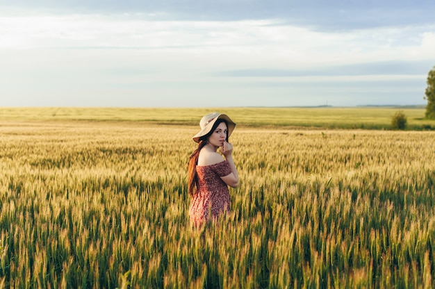 Mooie jonge vrouw bij zonsondergang in het veld