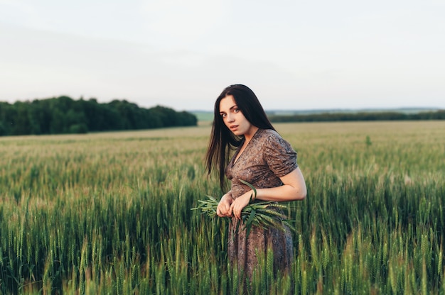 Mooie jonge vrouw bij zonsondergang in het veld