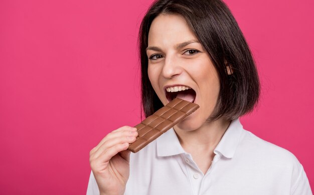 Mooie jonge vrouw bijt een reep chocolade