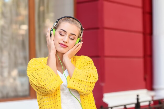 Mooie jonge vrouw buiten luisteren naar muziek