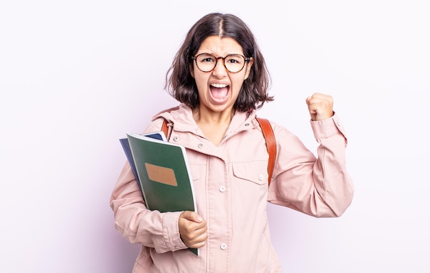 Mooie jonge vrouw die agressief schreeuwt met een boze uitdrukkingsstudent met boekenconcept