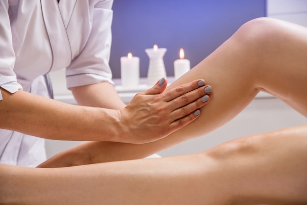 Mooie jonge vrouw die benen van massage met olie in kuuroordsalon genieten.