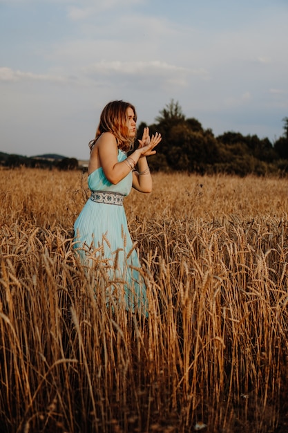 Mooie jonge vrouw die bij zonsondergang in het veld danst