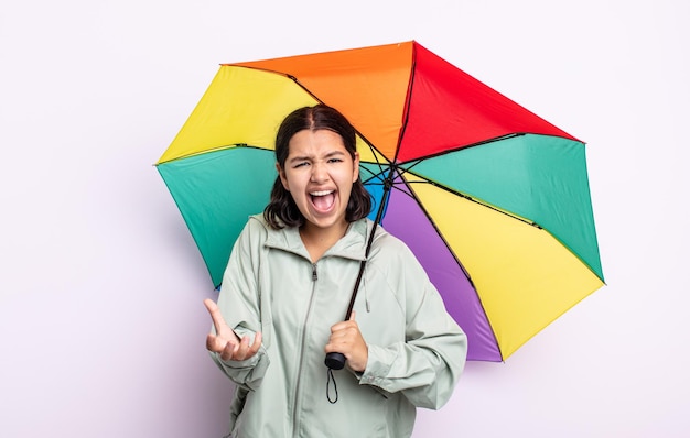 Mooie jonge vrouw die boos, geïrriteerd en gefrustreerd kijkt. regen en paraplu concept