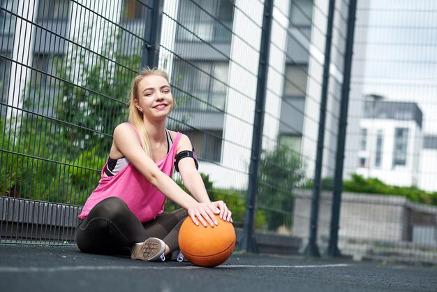 Mooie jonge vrouw die buiten basketbal speelt Het meisje op het sportveld