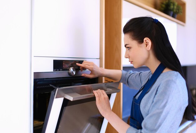 Mooie jonge vrouw die controleert hoe haar cake het doet in de oven