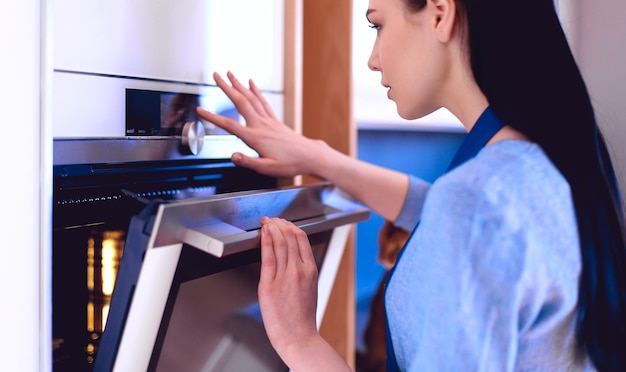 Mooie jonge vrouw die controleert hoe haar cake het doet in de oven