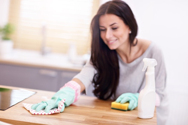 mooie jonge vrouw die de keuken schoonmaakt