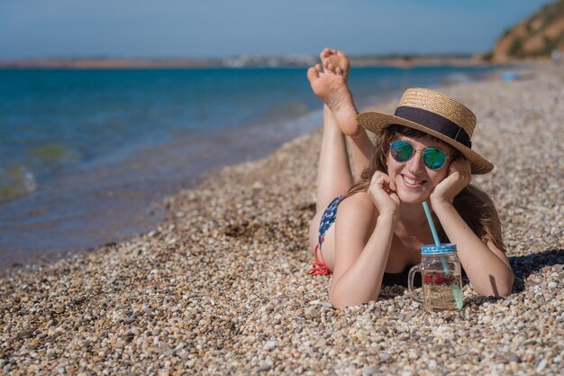 Mooie jonge vrouw die een cocktail drinkt op het strand Aantrekkelijk meisje dat een drankje aanbiedt Mooie vrouw die limonade drinkt