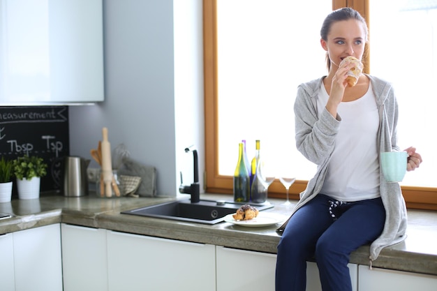 Mooie jonge vrouw die een digitale tablet in de keuken gebruikt