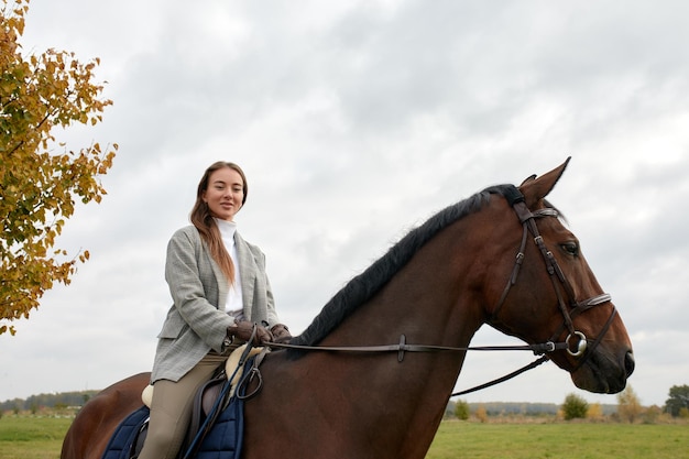 Mooie jonge vrouw die een paard berijdt op het veld Zijwaarts naar de camera Vrijheidsvreugdebeweging